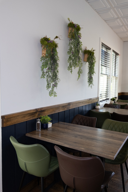 Warm tables and hanging greenery inside Brew Cafe